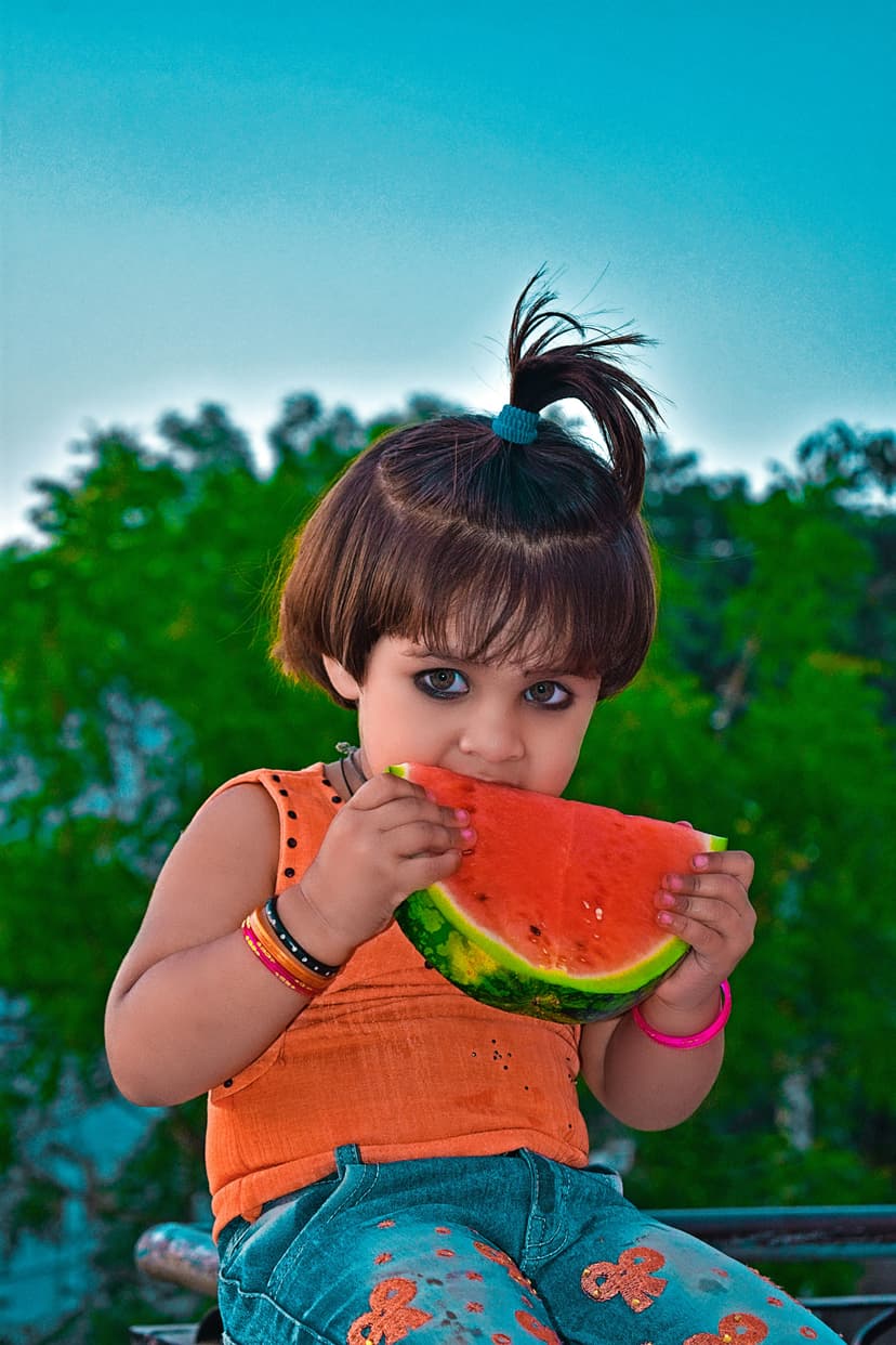 A little girl eating a piece of watermelon
