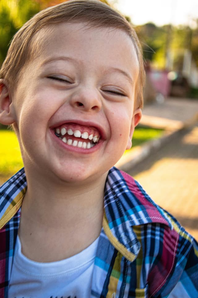 A young boy smiling and holding a cell phone